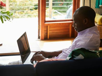 Man stretching his shoulders using an elastic band in a bright room.